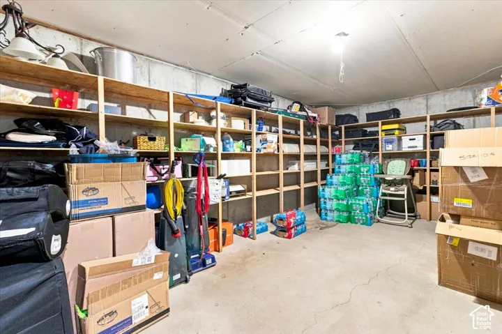 Storage area featuring concrete walls, a concrete floor, and extensive built-in wooden shelving units