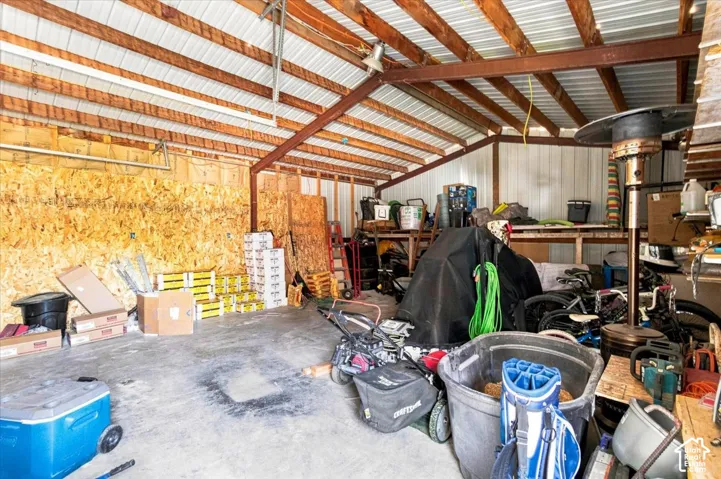 Workshop space featuring a concrete floor, exposed steel beam construction, metal ceiling, and oriented strand board (OSB) wall panels