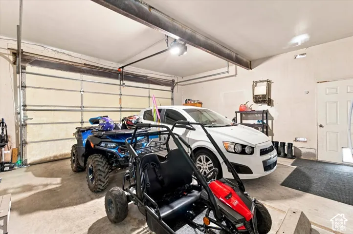 Attached garage featuring concrete flooring, steel beam ceiling supports, an overhead sectional door, and a secondary entry door