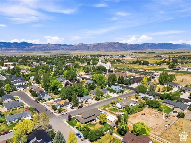 Aerial perspective of a residential neighborhood featuring mature trees, paved roadways, and mountain range scenery