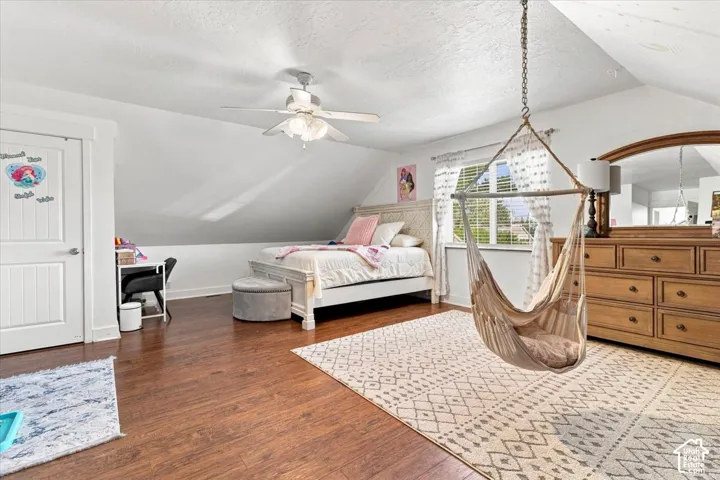 Vaulted ceilings, wood-finish flooring, and a multi-blade ceiling fan with integrated lighting
