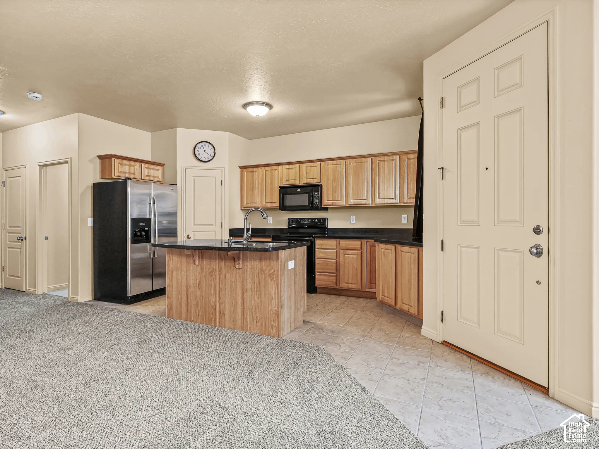 Kitchen featuring natural wood-finish cabinetry, a center island with a stone countertop, dark stone-surface countertops, and built-in stainless steel appliances