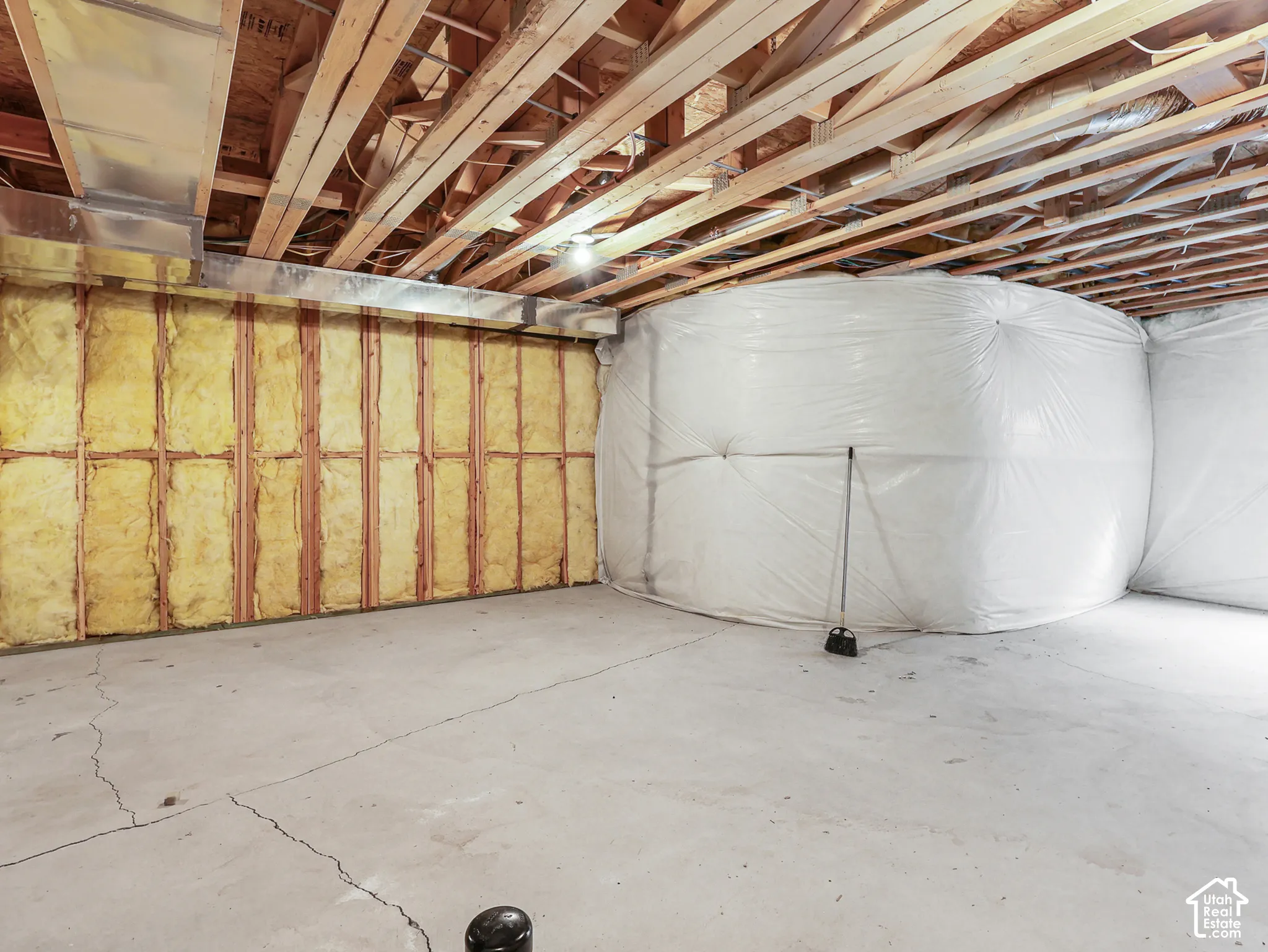 Unfinished lower level featuring exposed wood joist ceilings, concrete flooring, insulated wall panels, and vapor-barrier encased foundation walls