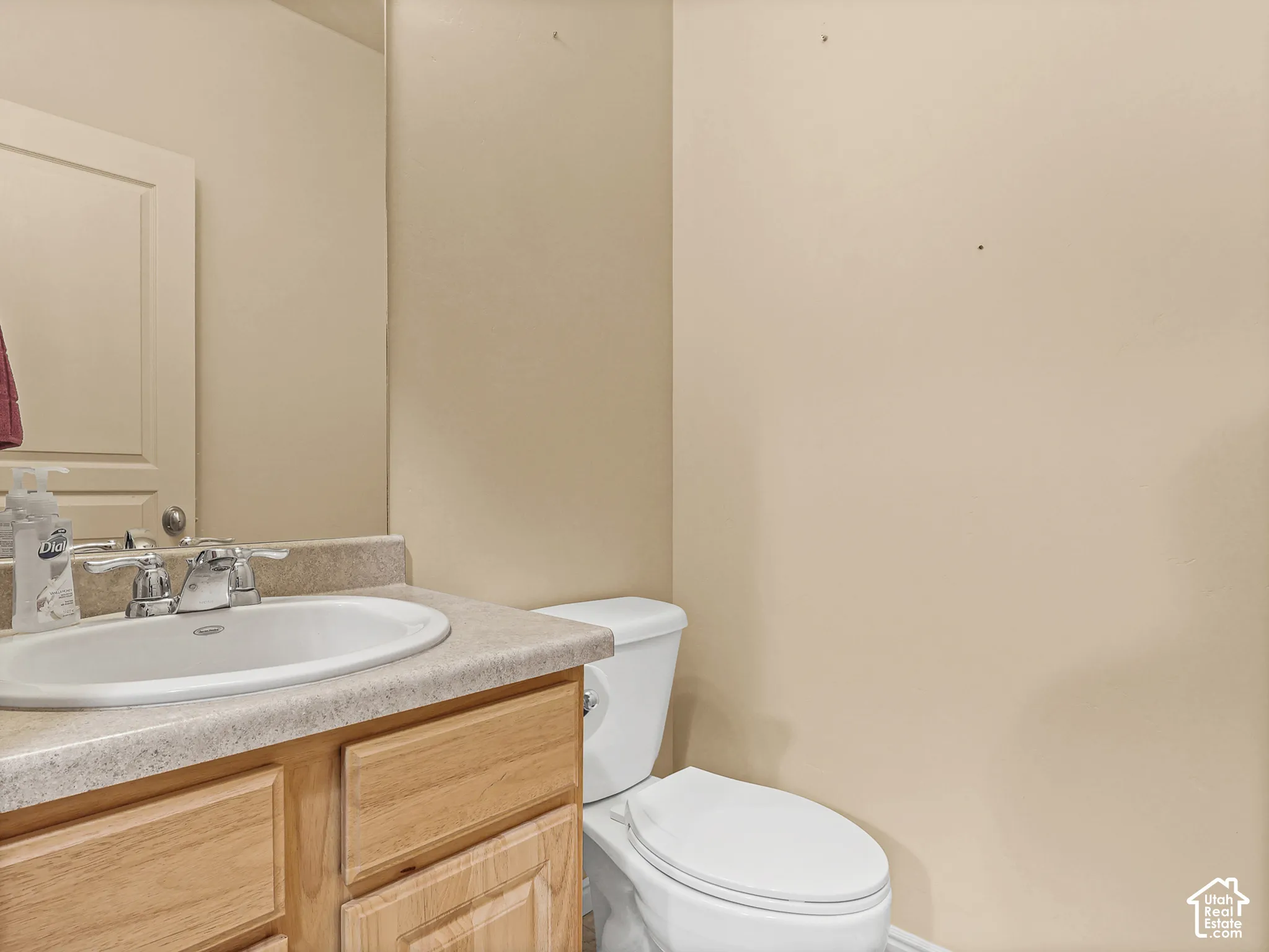 Wood-finish vanity featuring an integrated countertop, inset sink, polished chrome faucet, and expansive wall-mounted mirror