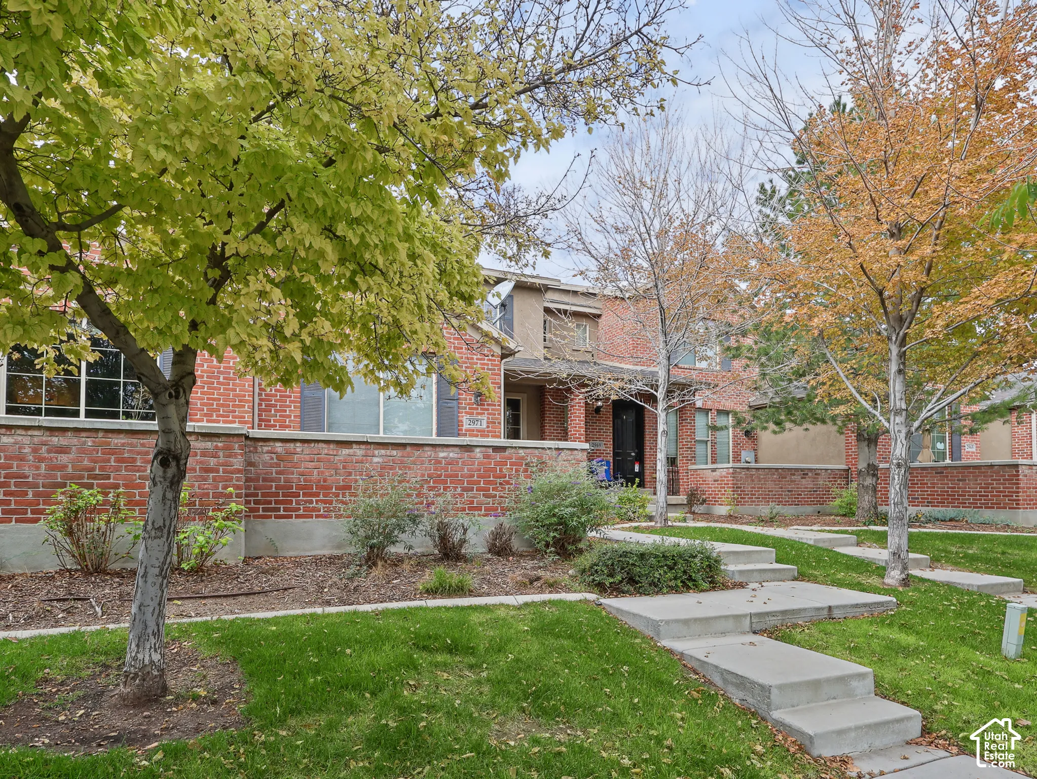 Brick exterior featuring recessed entry, low-maintenance landscaping, mature trees, and concrete paved walkways