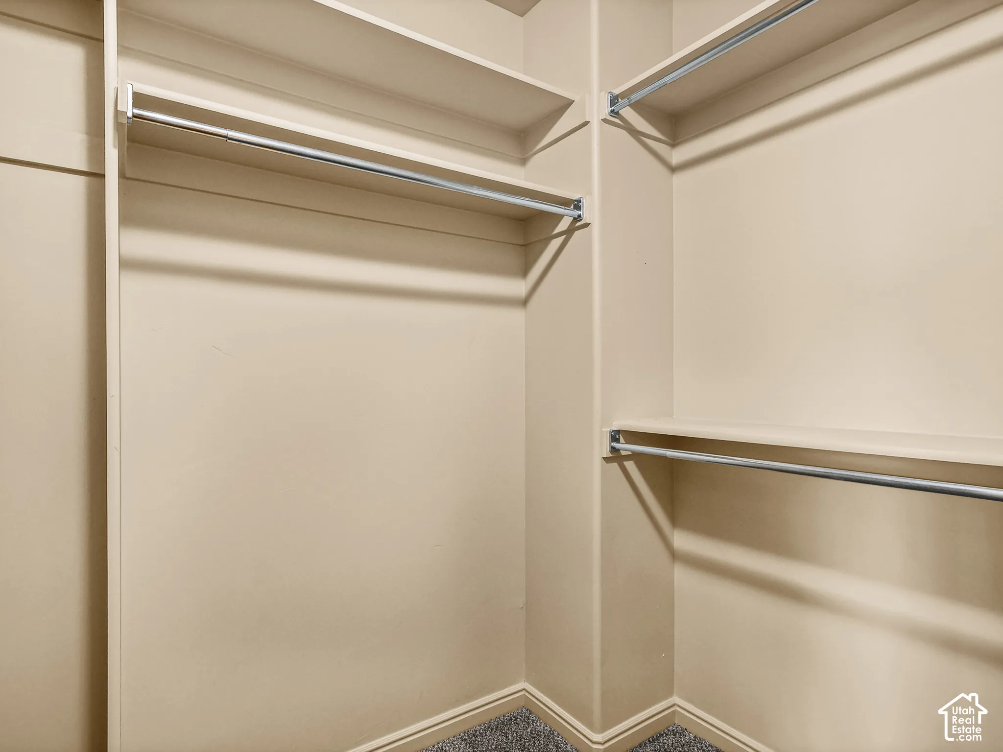 Walk-in storage area featuring tiered built-in shelving and dual-level metal hanging rods