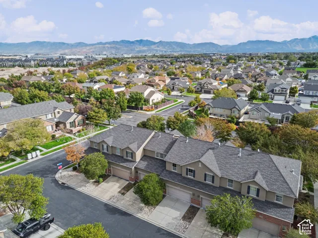 Multi-level residential building featuring asphalt shingle roofing, brick and stucco exterior, attached garage parking, and mountain scenery