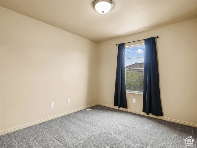 Neutral-toned walls, wall-to-wall carpet, single-pane window with grid detailing, and a flush-mount ceiling light fixture