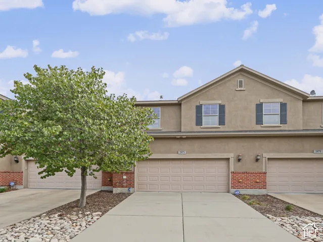 Stucco and brick facade featuring multi-car garages, decorative shutters, and concrete driveways