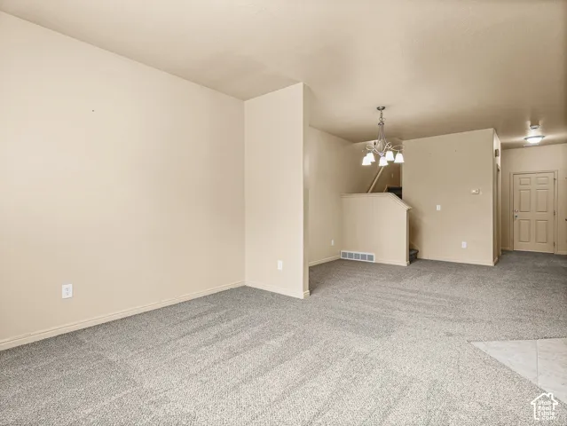 Neutral-toned interior featuring wall-to-wall carpeting, a multi-arm chandelier, and a paneled entry door