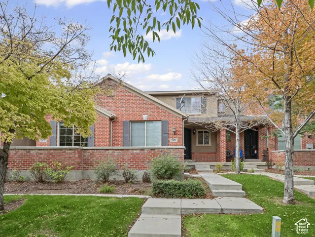 Red brick exterior featuring a multi-level facade, grey window shutters, a covered porch entrance, and concrete walkway