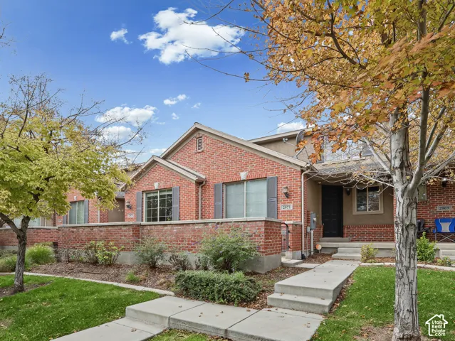 Red brick exterior featuring a low-profile stone retaining wall, concrete walkway, and shuttered windows