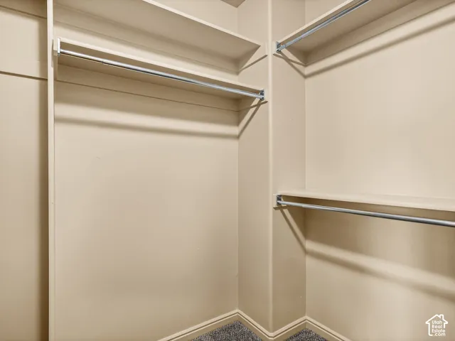 Walk-in storage area featuring tiered built-in shelving and dual-level metal hanging rods