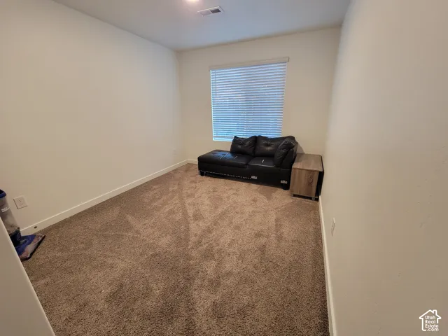 Neutral-toned carpeted flooring, walls finished in a soft neutral palette, and a window featuring horizontal blinds