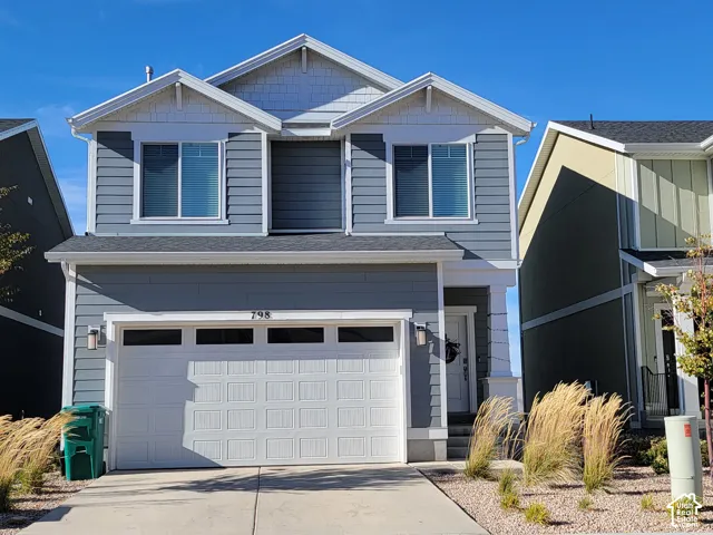Two-story exterior featuring dual-gable roofline, horizontal lap siding, shake-style siding accents, and a multi-panel garage door with transom windows