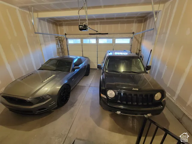 Two-car garage featuring concrete flooring, an automatic overhead door opener, and paneled garage door with horizontal glass windows