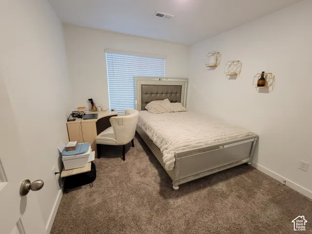 Neutral-toned interior space featuring plush carpeting and a window equipped with horizontal blinds