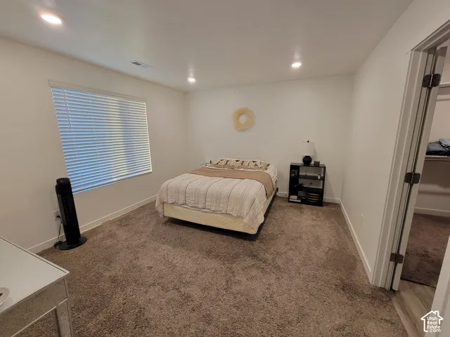Neutral-toned carpeting, recessed ceiling lighting, and a large window featuring horizontal blinds