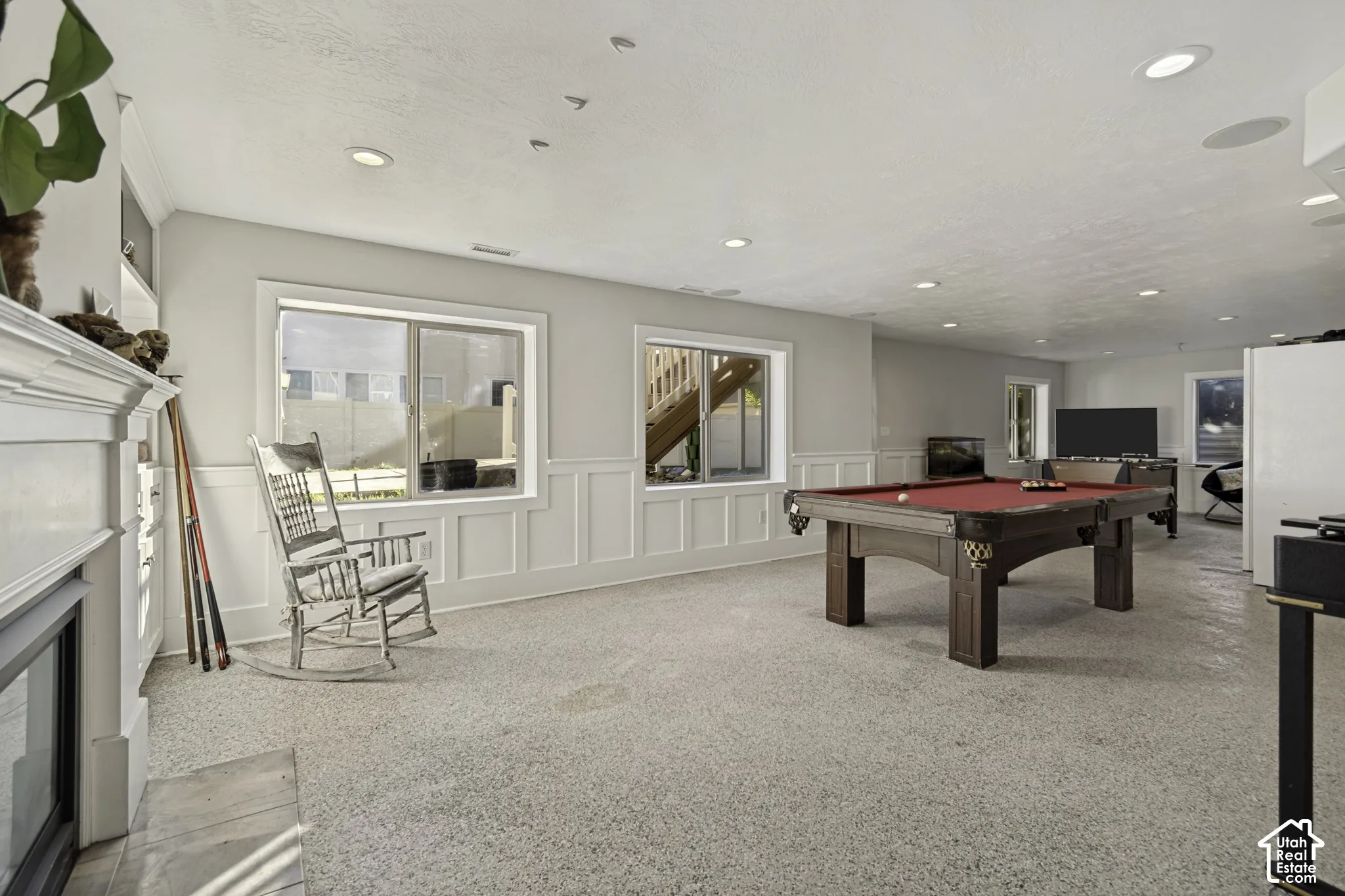 Interior space featuring white wainscoting, recessed lighting, neutral carpeting, and a fireplace with a decorative mantel
