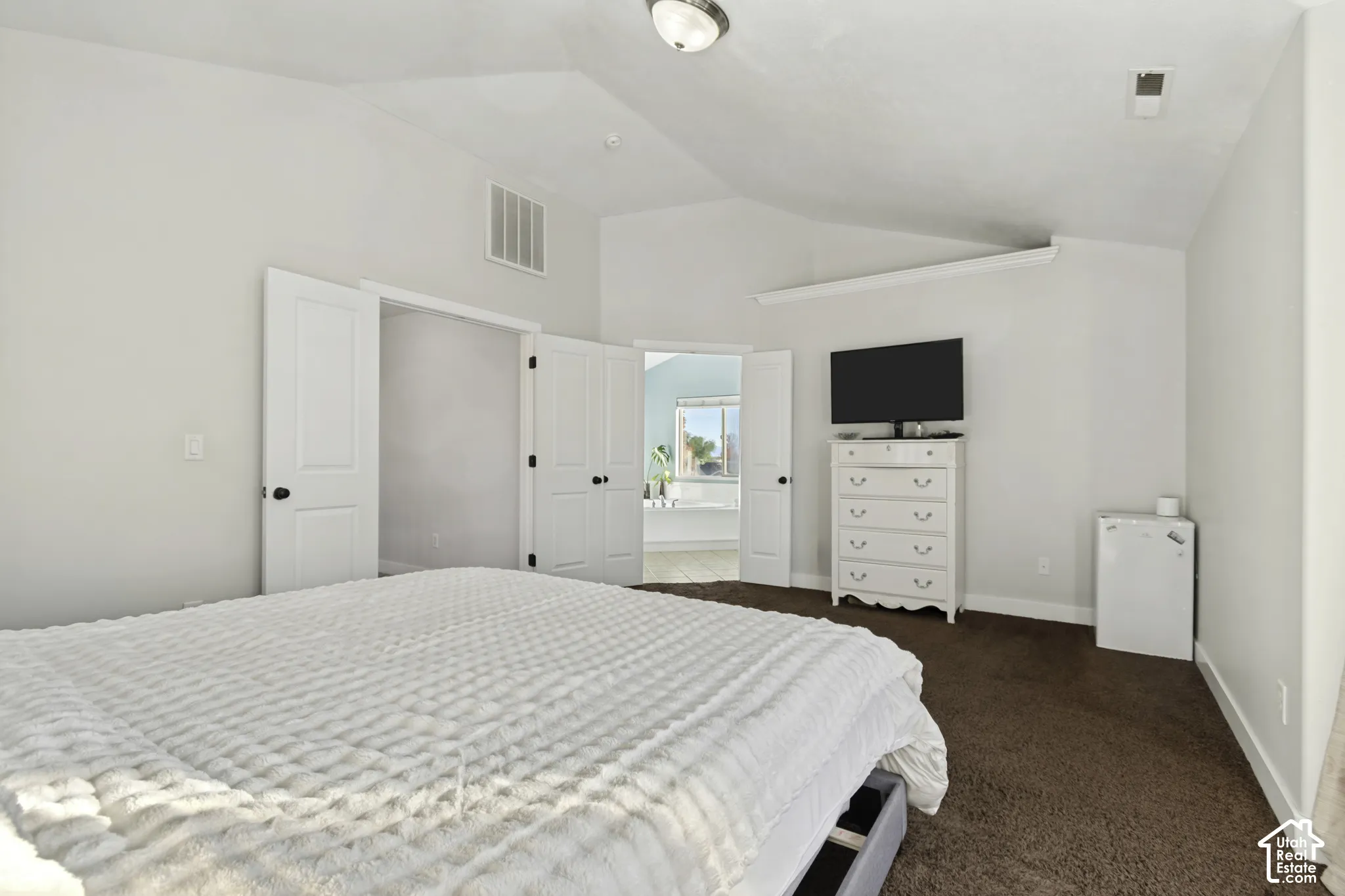 Vaulted ceilings, neutral wall palette, carpeting, and multi-panel interior doors