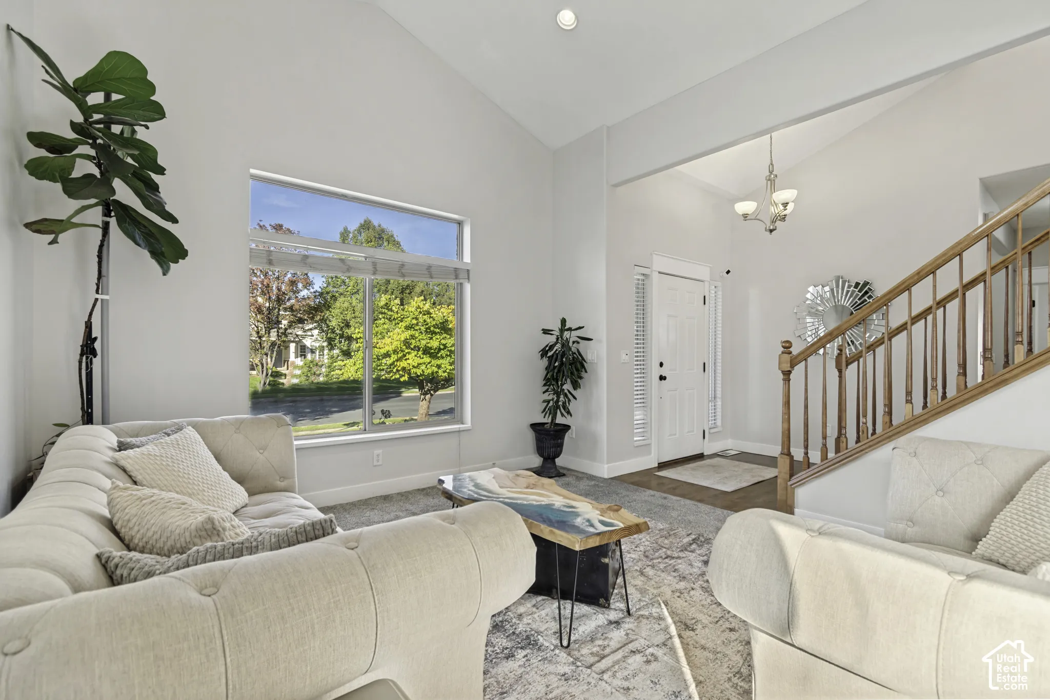 Vaulted ceilings, large picture window, and wooden staircase with decorative balusters
