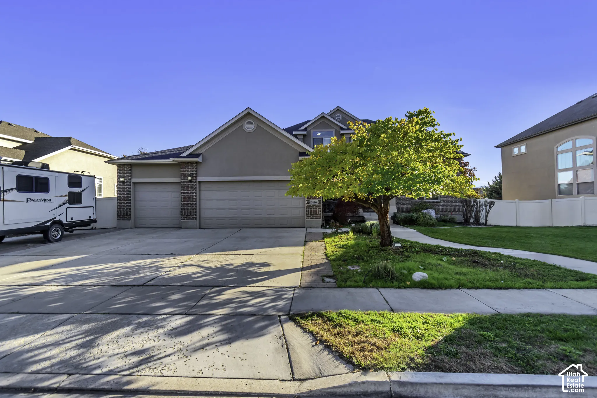 Stucco exterior featuring brick accents, a three-car garage, and concrete driveway