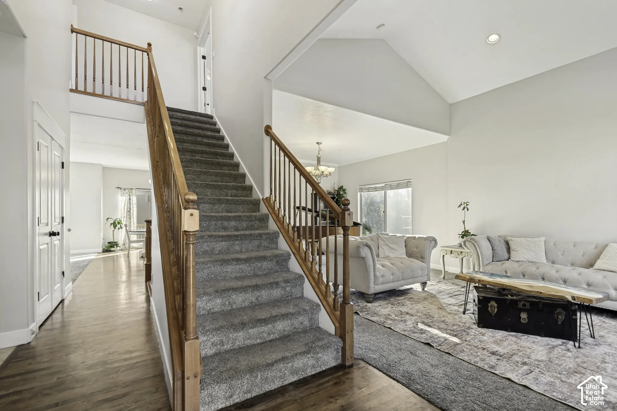 Open-concept interior featuring vaulted ceilings, staircase with wooden balusters, recessed lighting, and wood-finish flooring