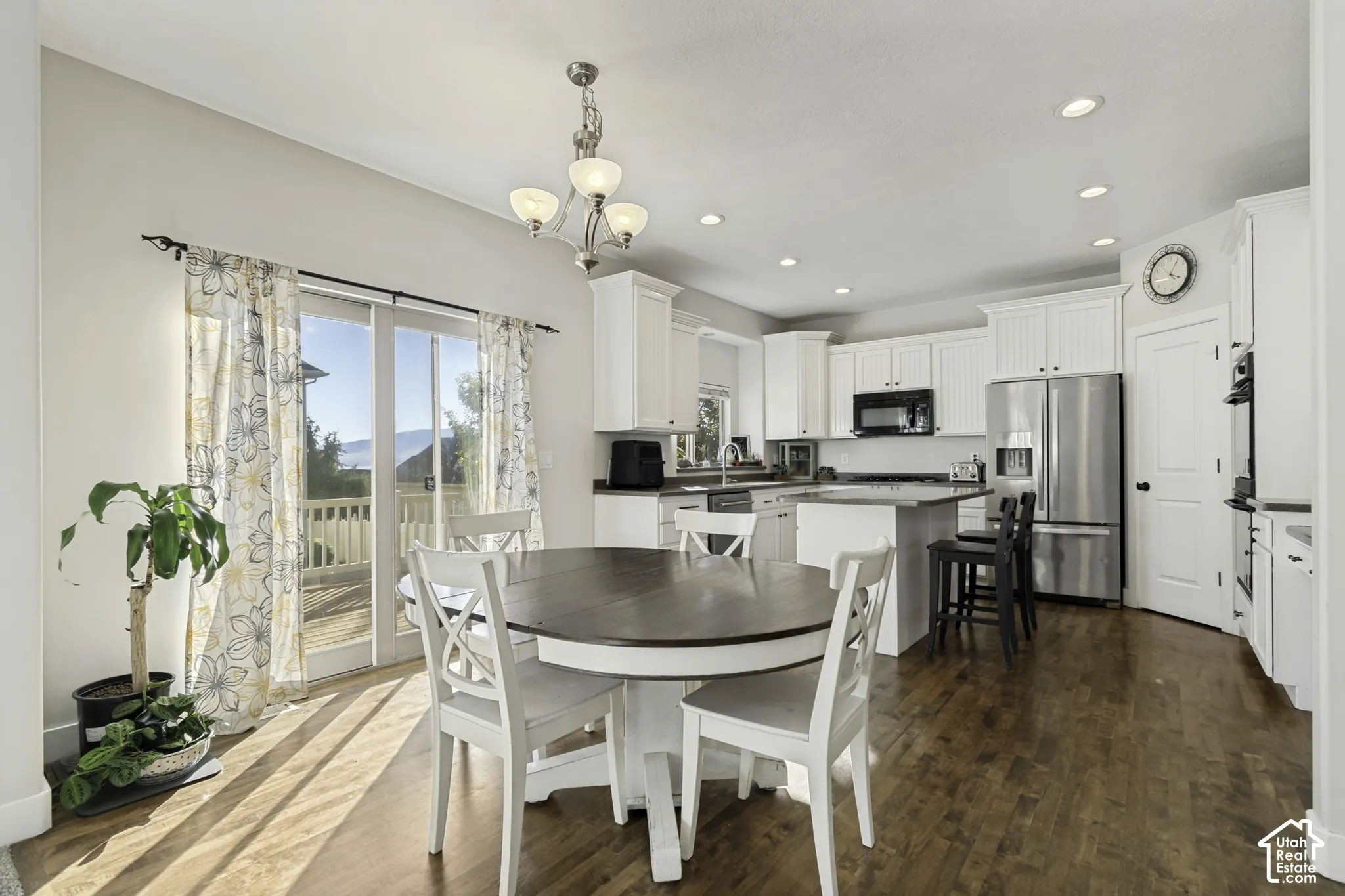 Kitchen featuring white shaker-style cabinetry, a center island with stone countertop, stainless steel appliances, wood-finish flooring, and recessed lighting