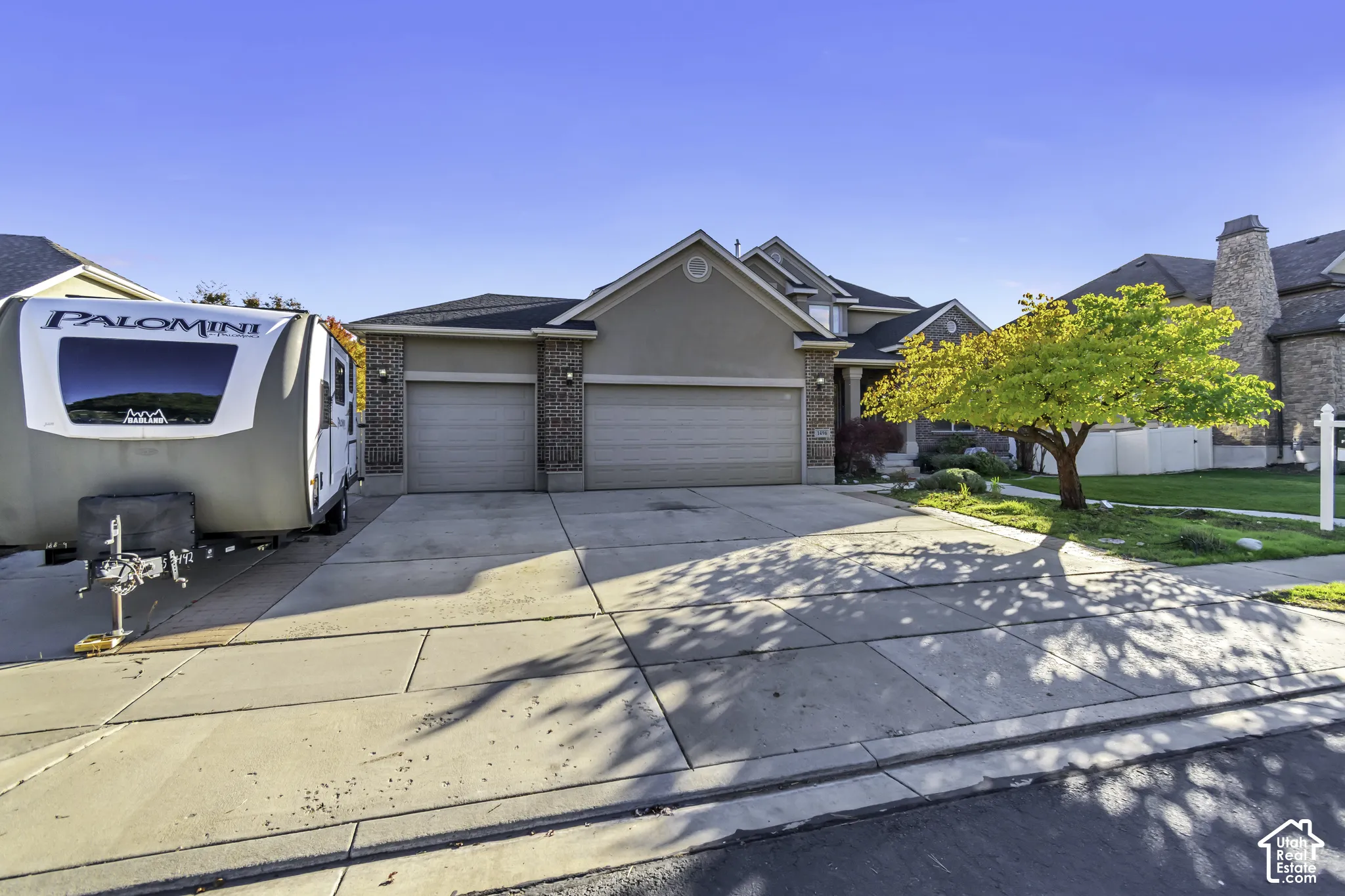 Exterior featuring a multi-gable roofline, a combination of stucco and brick siding, and an expansive concrete driveway leading to a three-car garage