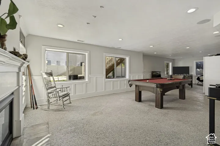 Interior space featuring white wainscoting, recessed lighting, neutral carpeting, and a fireplace with a decorative mantel