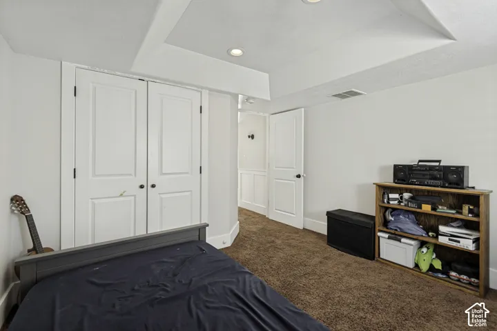Room featuring a tray ceiling, recessed lighting, double-door closet, and interior doors with oil-rubbed bronze hardware