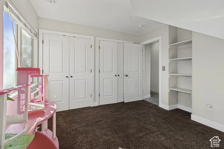 Room featuring neutral wall tones, textured carpeting, dual-panel closet doors, and built-in shelving