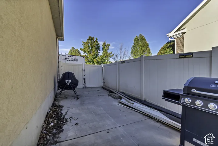 Concrete side yard featuring a white vinyl privacy fence and gated access
