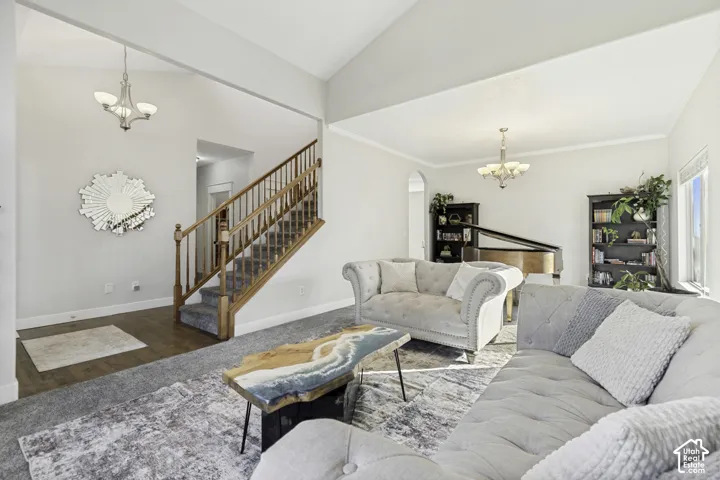 Vaulted ceilings, staircase with a wooden handrail and balusters, and dual tiered chandeliers