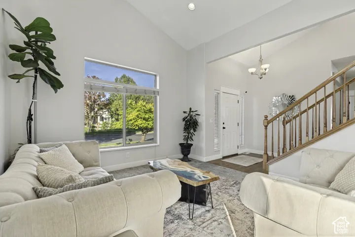 Vaulted ceilings, large picture window, and wooden staircase with decorative balusters