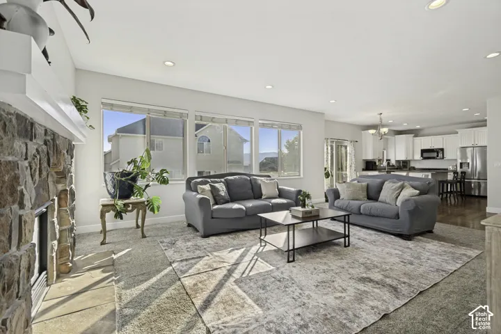 Living area featuring a floor-to-ceiling stone fireplace, recessed lighting, expansive picture windows, and wood-finish flooring throughout the kitchen area