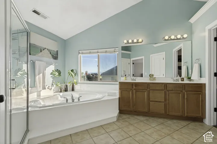 Vaulted ceiling, corner soaking tub, dual-sink wood cabinetry, large vanity mirror, and glass-enclosed shower