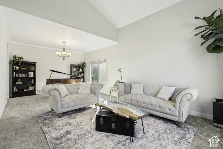 Vaulted ceilings, neutral wall palette, plush wall-to-wall carpeting, and a multi-arm chandelier
