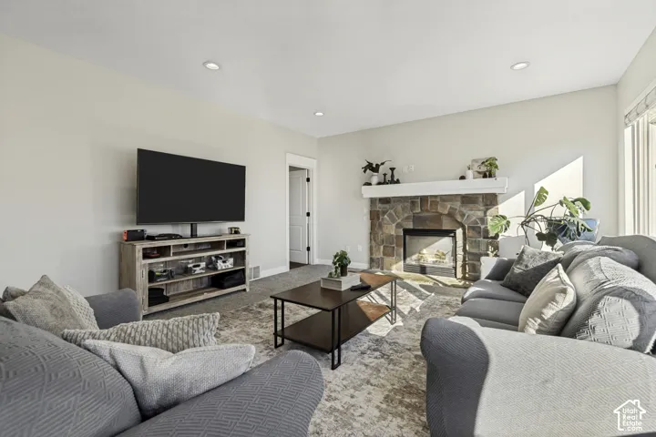 Living area featuring recessed lighting, a stone-surround fireplace with a mantel, and neutral wall tones