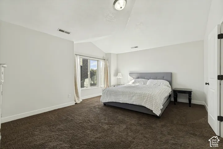 Spacious room featuring a vaulted ceiling, neutral wall tones, large window, and wall-to-wall carpeting