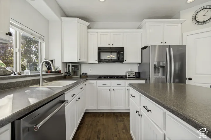 Kitchen featuring white shaker-style cabinetry, solid-surface countertops, wood-finish flooring, stainless steel appliances, and a undermount sink with a gooseneck faucet