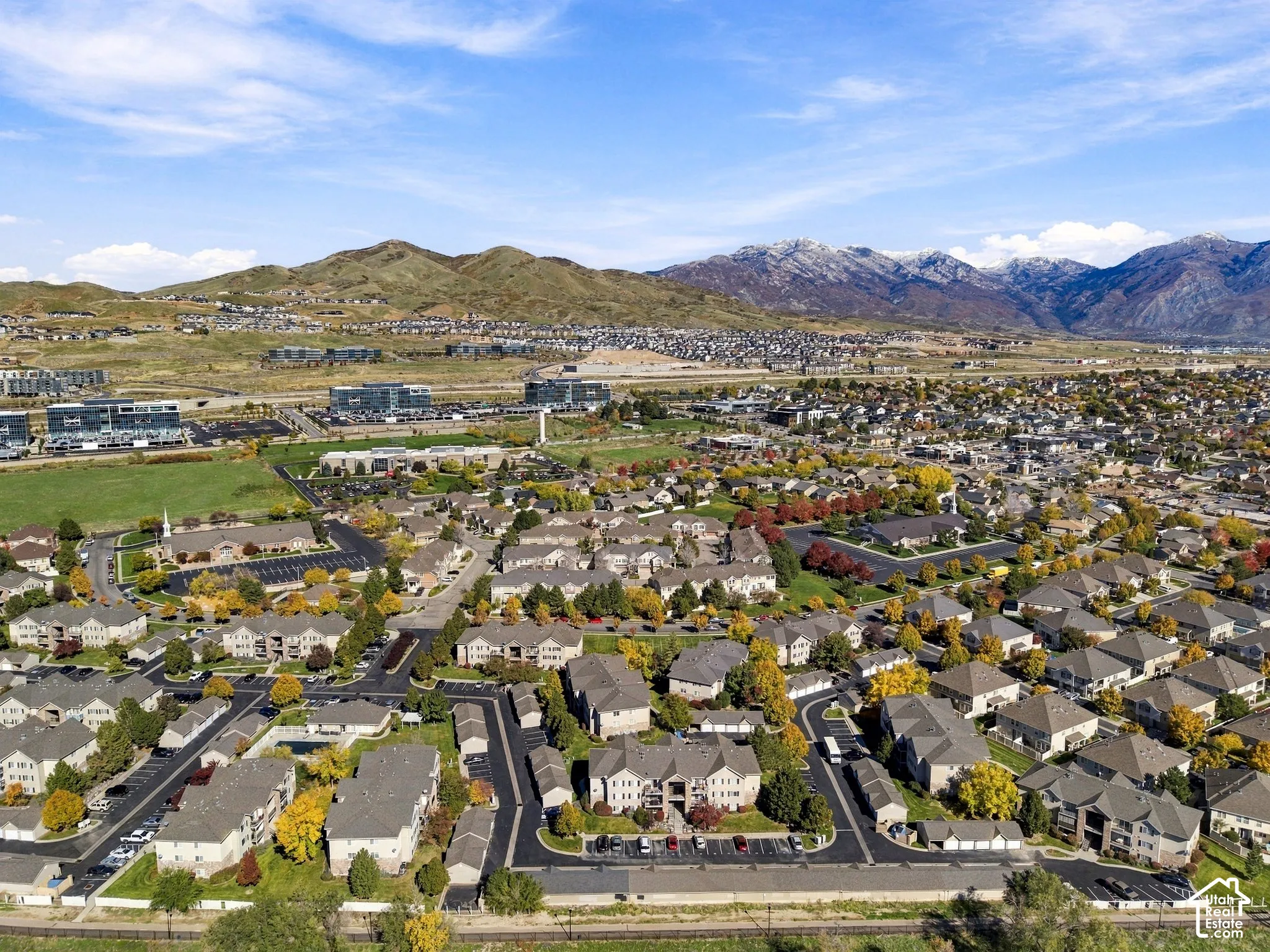Aerial perspective featuring expansive mountain range backdrop, established community landscaping, paved roadways, and multi-unit residential structures