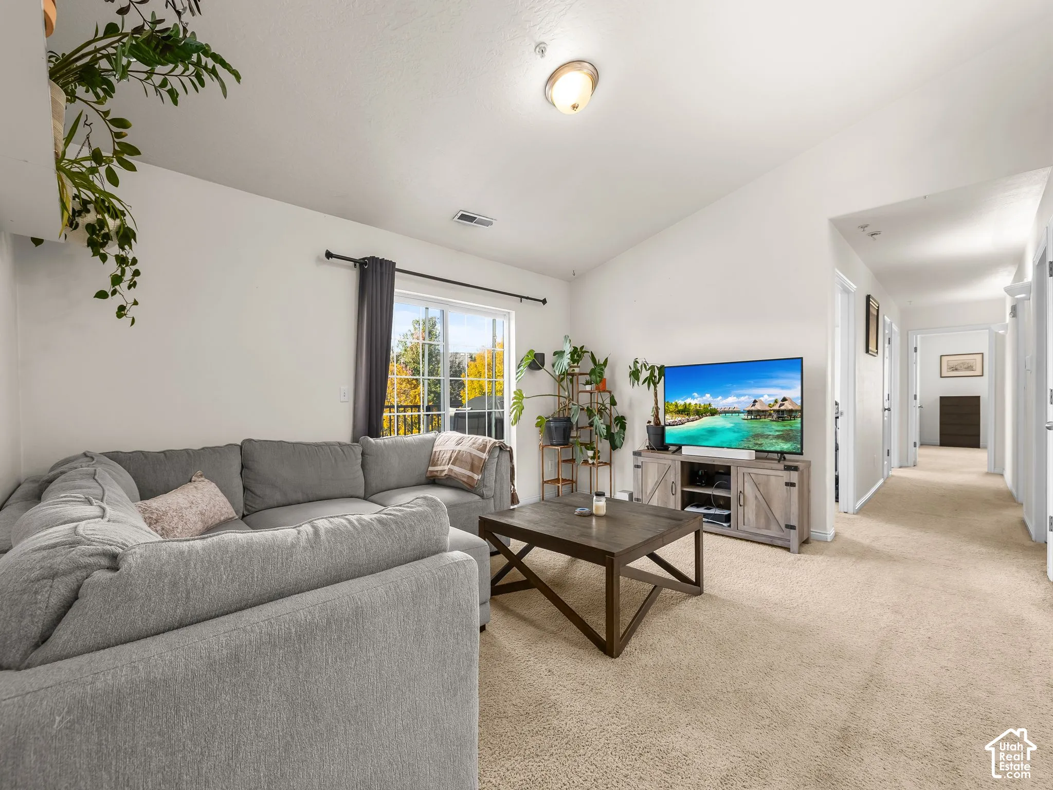 Living area featuring vaulted ceilings, neutral wall-to-wall carpeting, and a sliding glass door providing exterior access