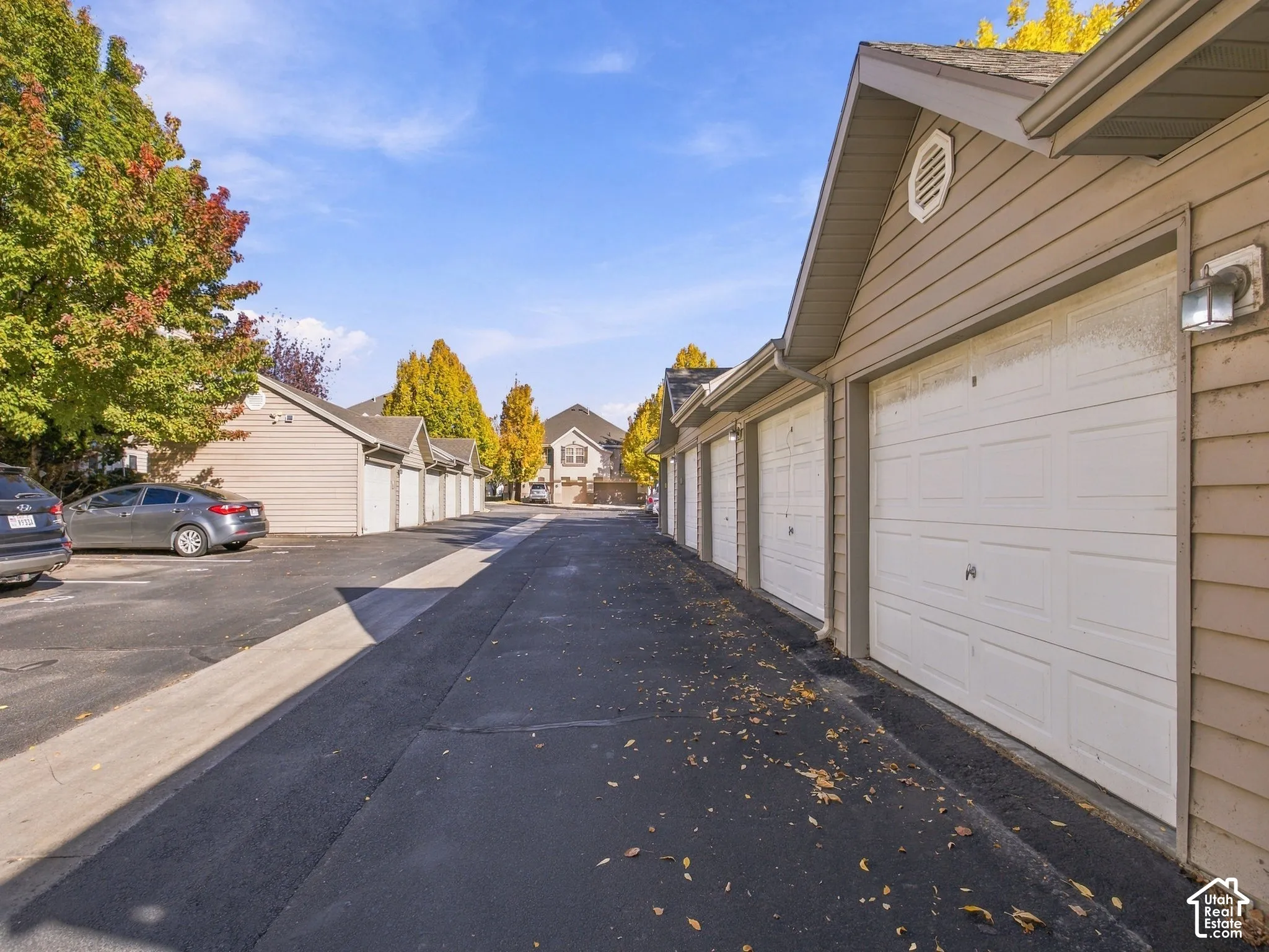 Row of detached garage units featuring horizontal siding, asphalt driveway, and wall-mounted exterior light fixtures