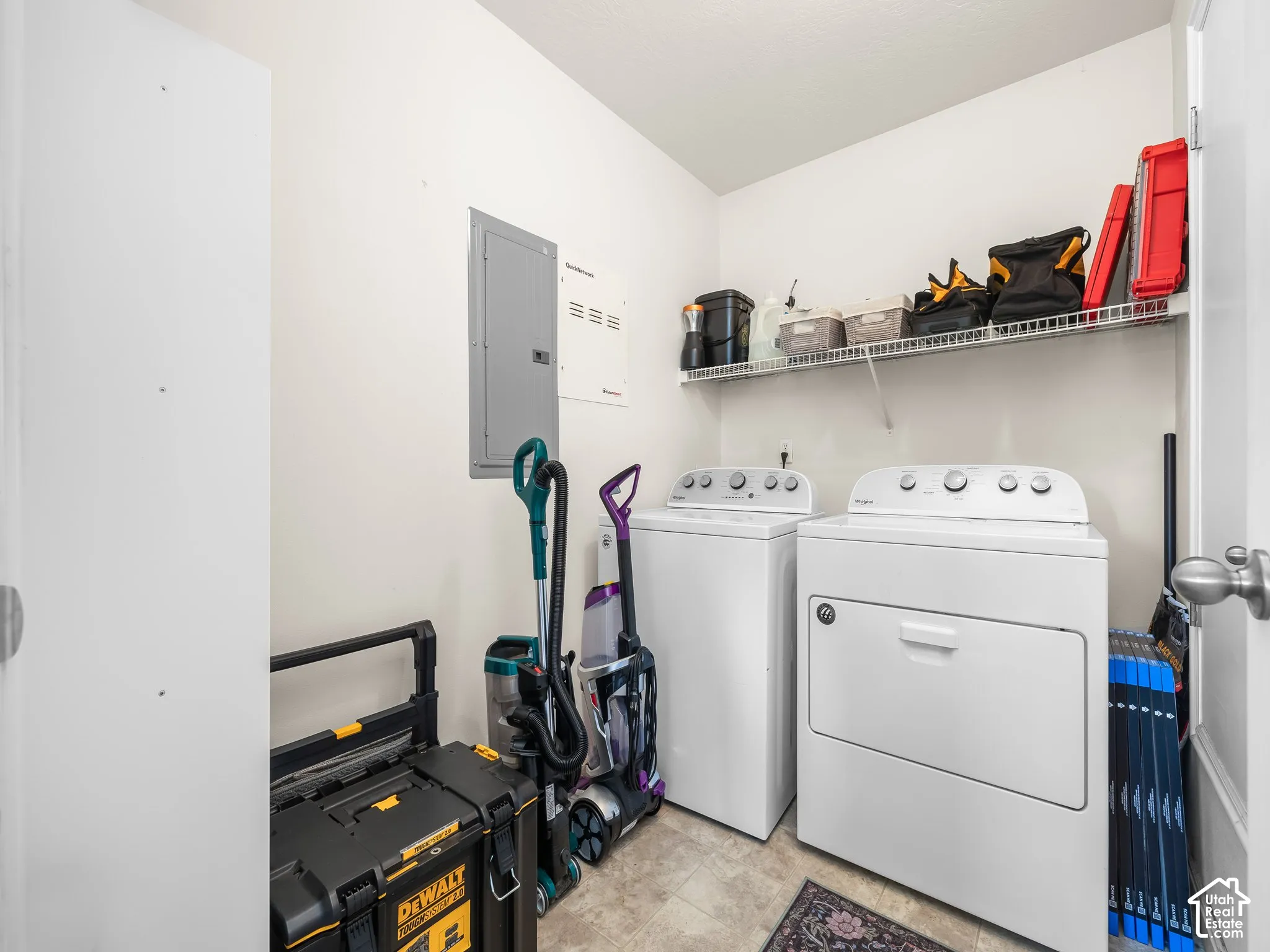 Dedicated utility space featuring a built-in wire shelving system, neutral resilient flooring, and a flush-mounted electrical service panel