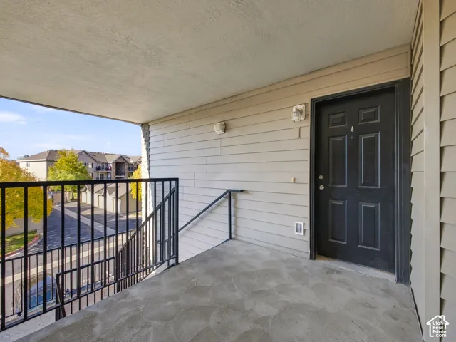 Covered exterior landing featuring horizontal siding, a solid entry door with a peephole, and metal railing