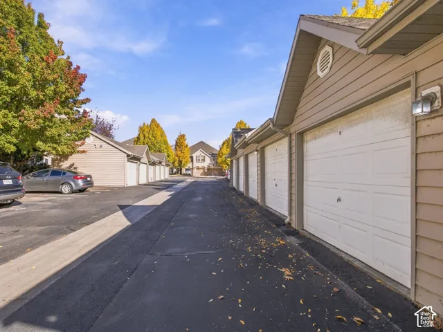 Row of detached garage units featuring horizontal siding, asphalt driveway, and wall-mounted exterior light fixtures