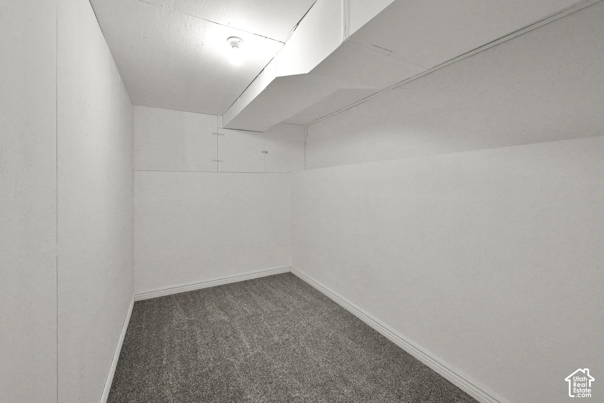 Interior space featuring neutral wall finish, gray carpeting, and structural ceiling soffit