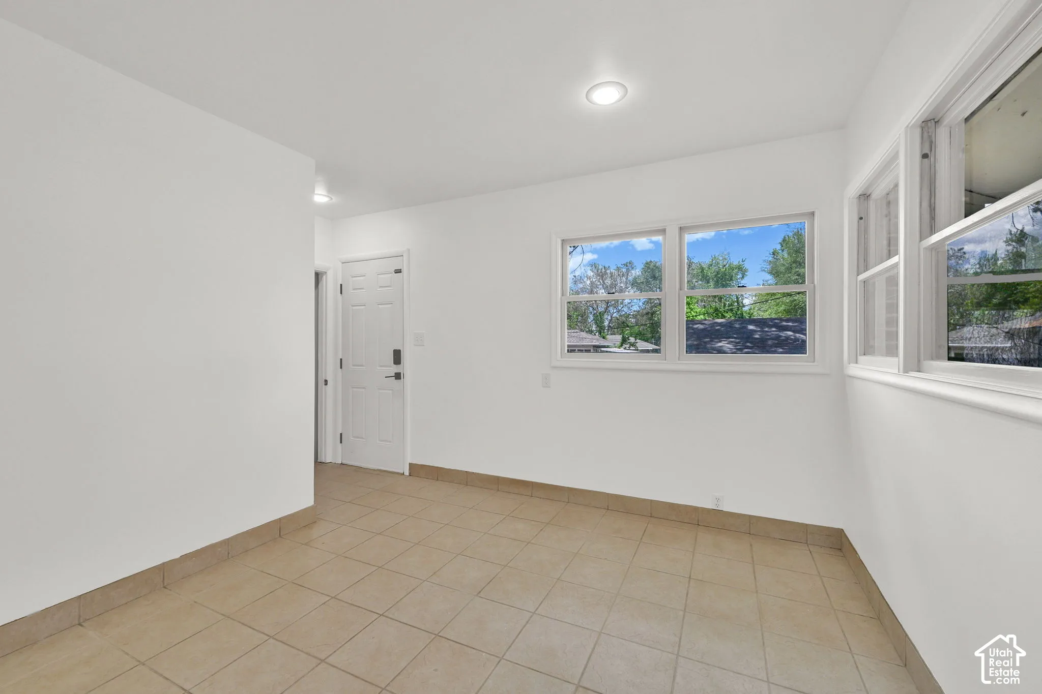 Neutral-toned tile flooring, recessed ceiling lighting, and large windows providing natural light
