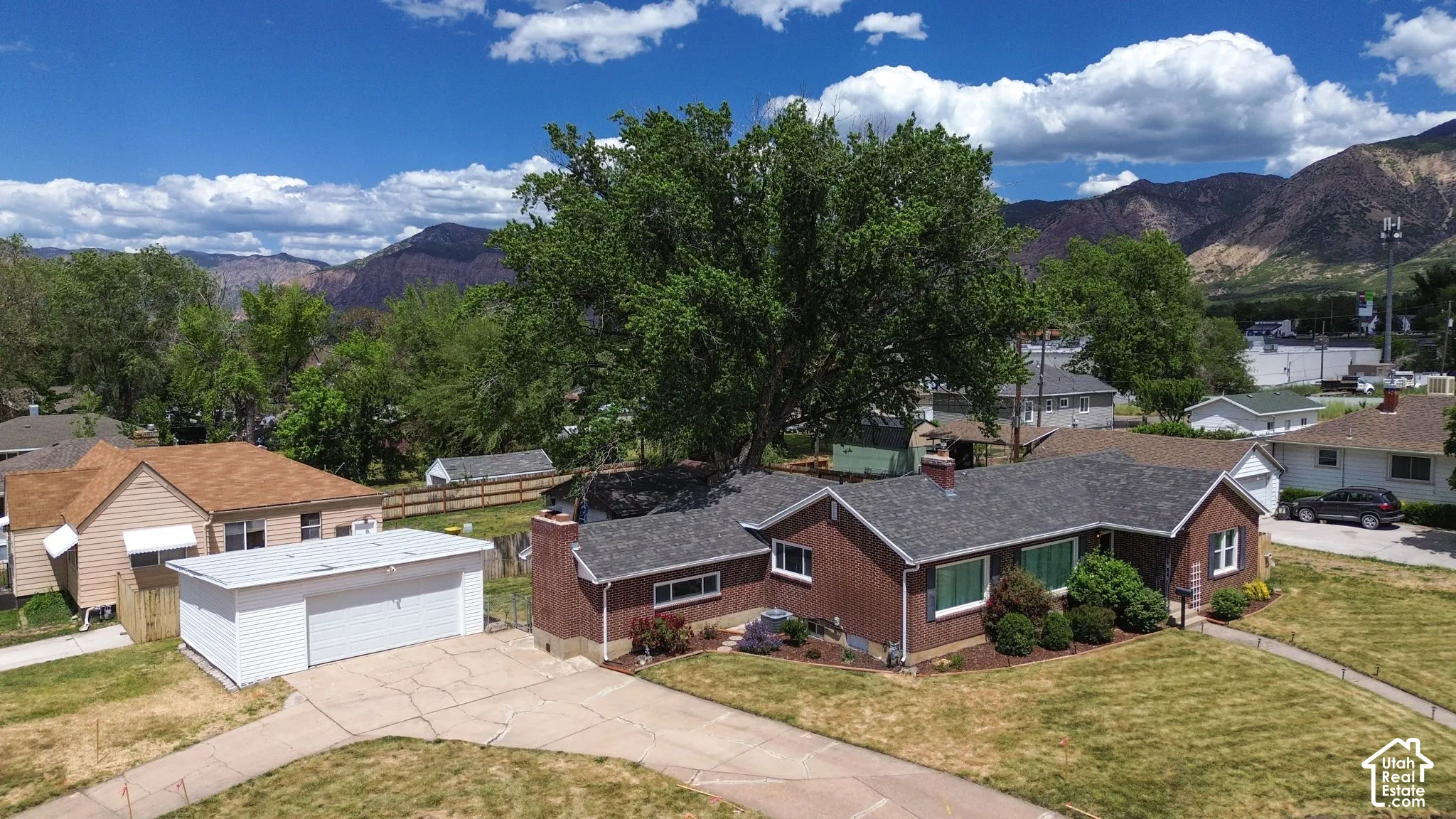 Single-story brick exterior residence featuring a detached garage, concrete driveway, and mountain backdrop
